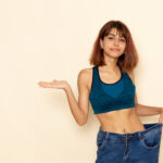 Mulher usando calça larga após emagrecer e perder medidas corporais