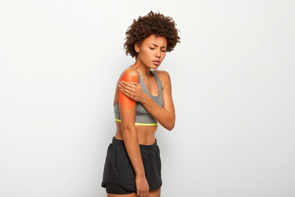 Mulher sentindo dor muscular no braço após treino de força